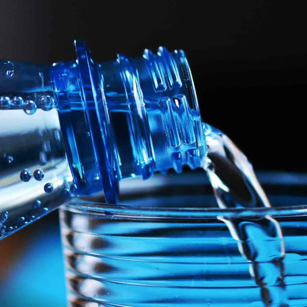 Water is poured out of a bottle into a glass.