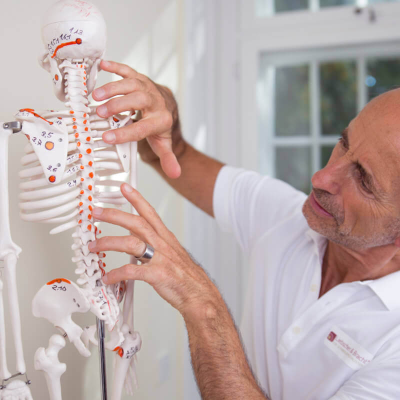 Roland Liebscher-Bracht pointing at an osteopressure point on a skeleton.