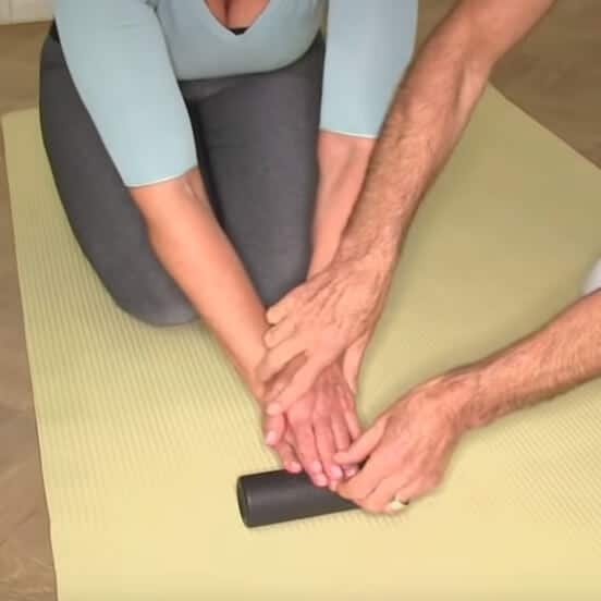 A woman is using a foam roller to treat her fingers.