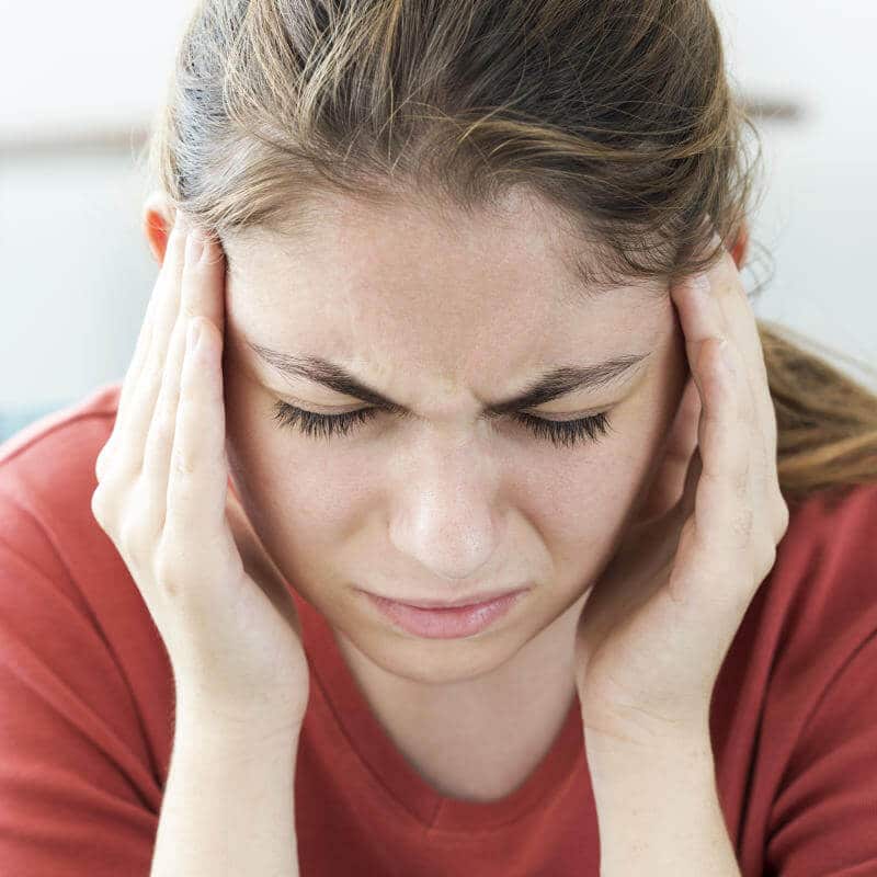 A woman rubbing her temples in pain.