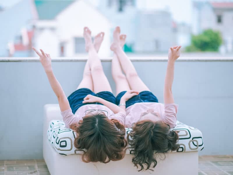 A pair of girls lying on their backs, mirroring their actions.