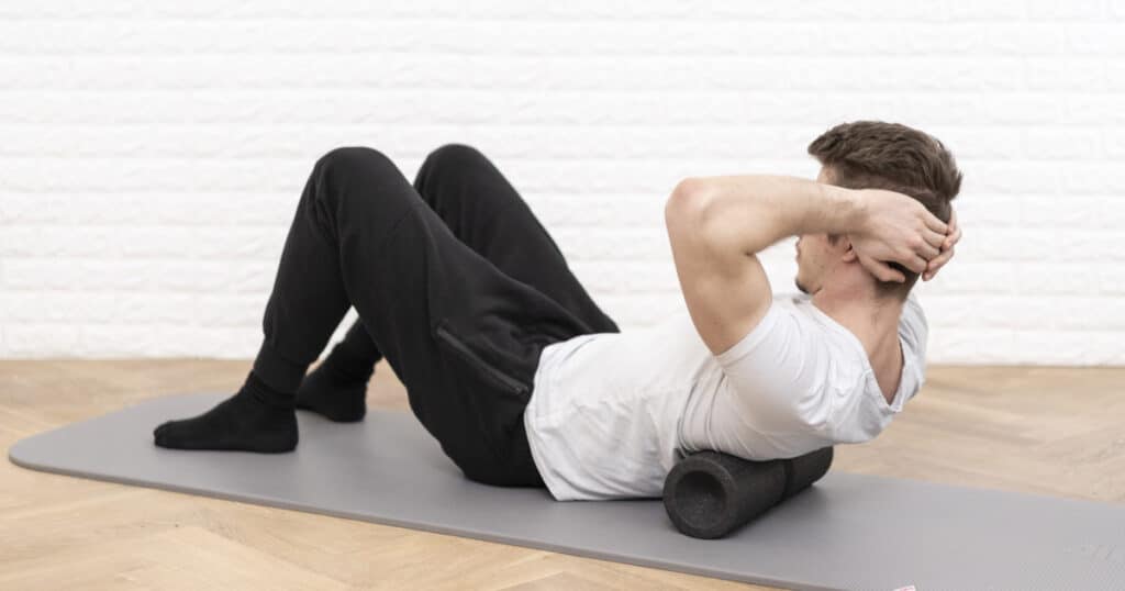 A man is using a fascia foam roll to ease the tension in his back