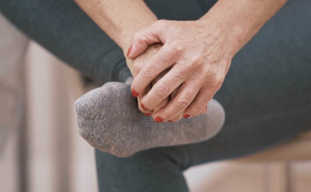A woman is using the spherical handle to perform Osteopressure on her foot.