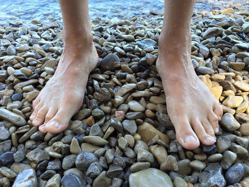 Barefoot feet on pebbles.