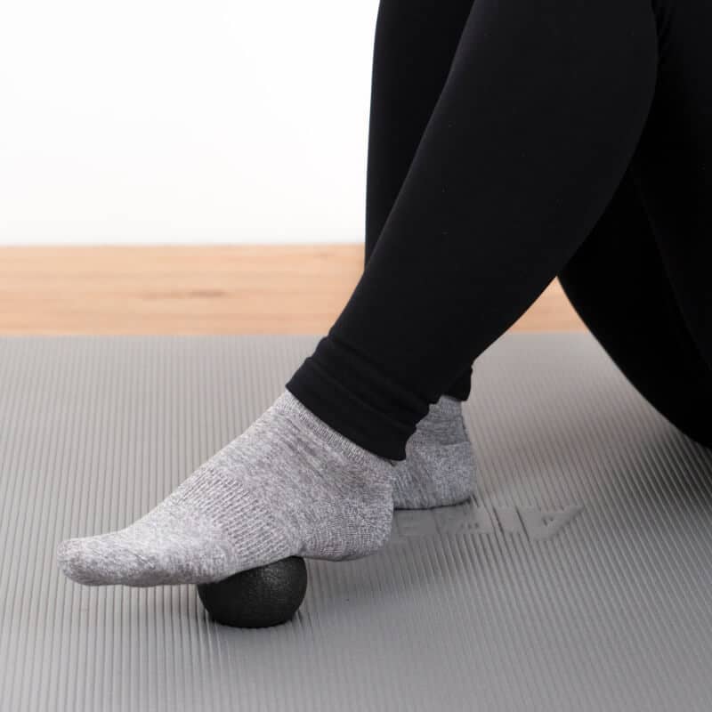 A woman is foam rolling her foot.