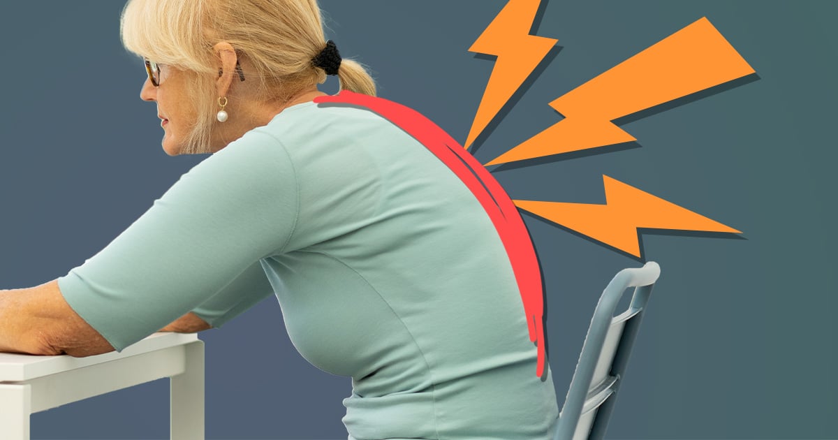 A woman with a hunchback is sitting at a desk.
