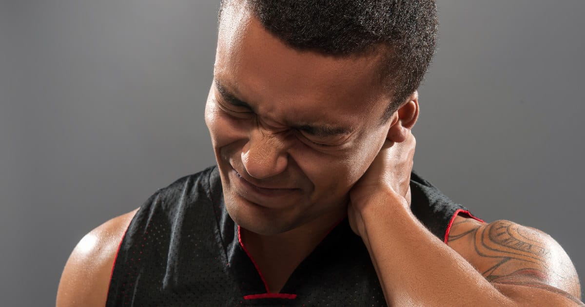 A man is clutching his aching neck, his eyes are closed in pain.