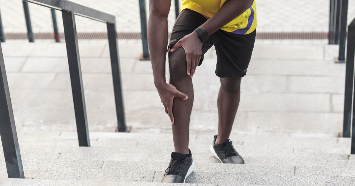 A man clutching his hurting knee.