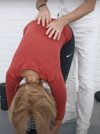 A woman is bending forward from the waist.