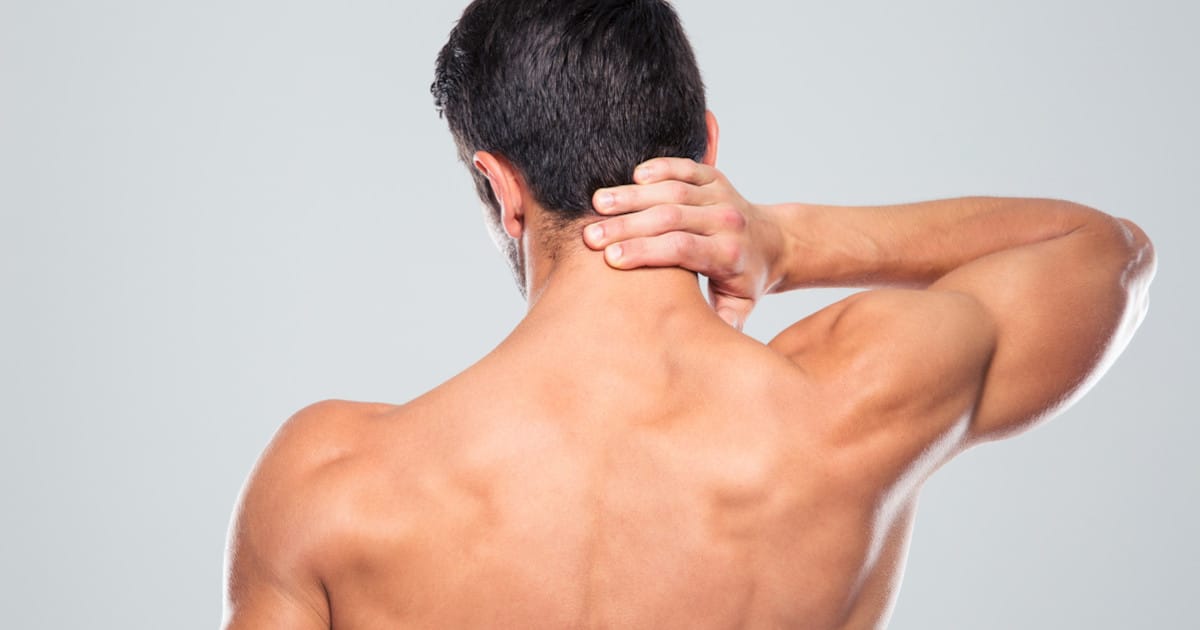 Shot of the back of a man, he's touching his neck.
