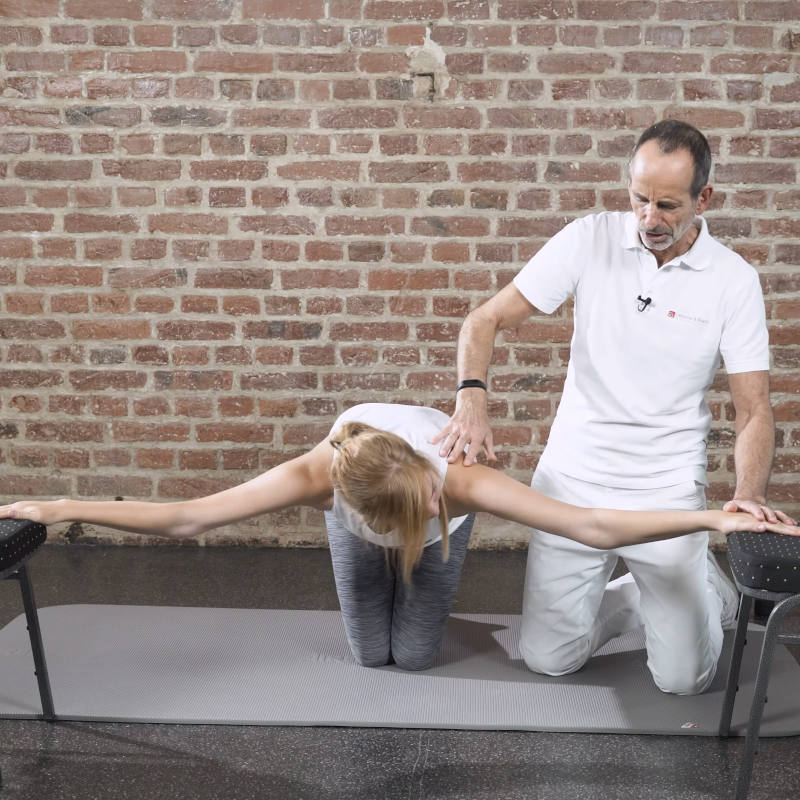 A woman is about to hang between two chairs.