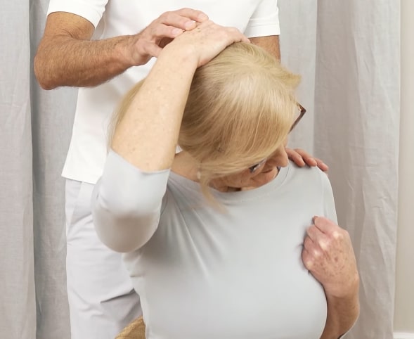 A woman is leaning her head to the side, stretching to relieve tinnitus.