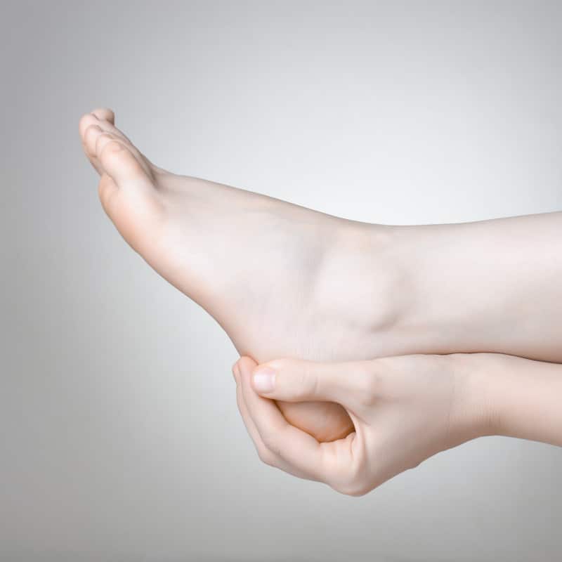 Closeup of a foot. A hand is touching the heel.