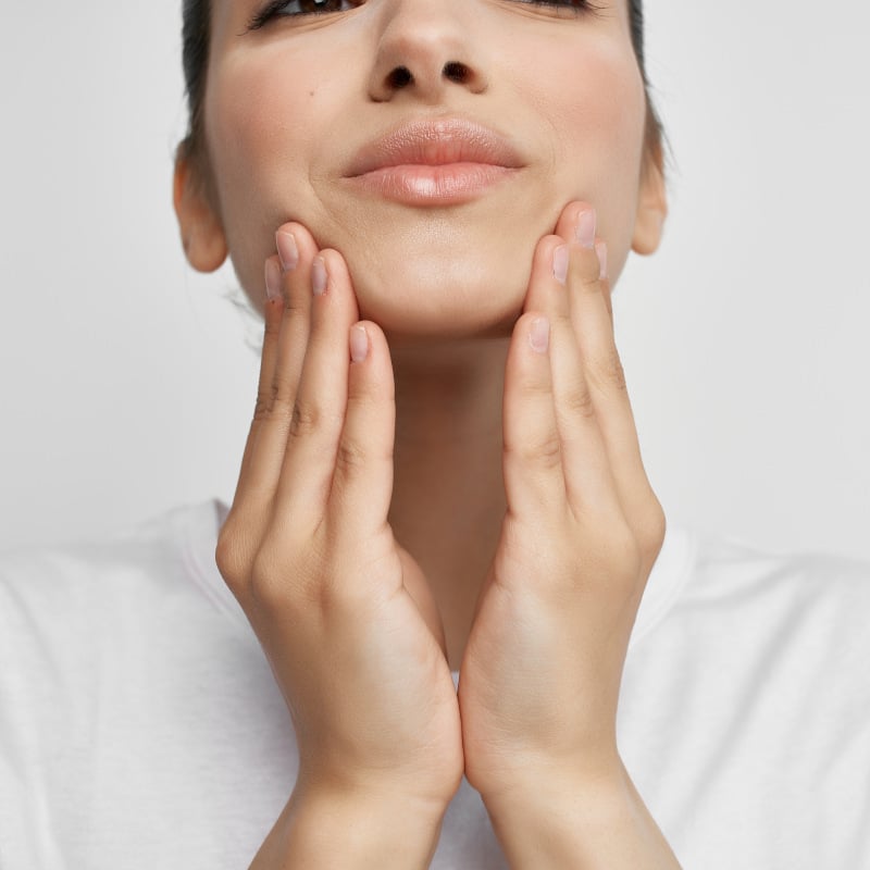 Closeup of a woman touching her jaw.