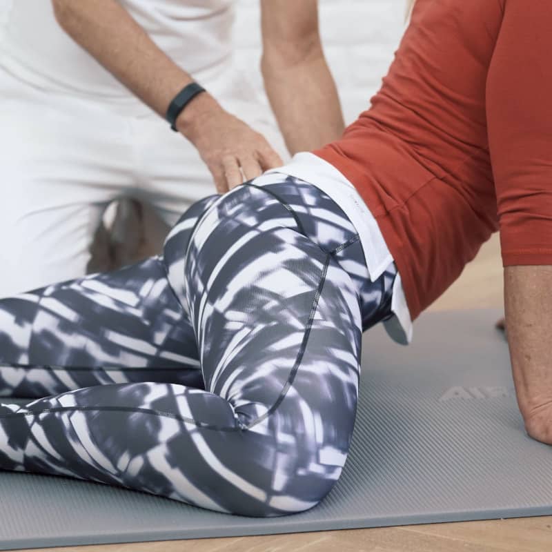 Closeup of a woman leaning her pelvis toward the floor.