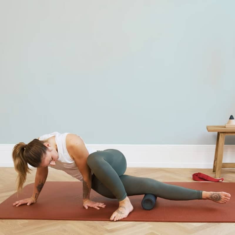 A woman is balancing her outer right leg against the Midi Foam Roller.